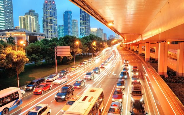 City expressway traffic at dusk, with light trails under an overpass